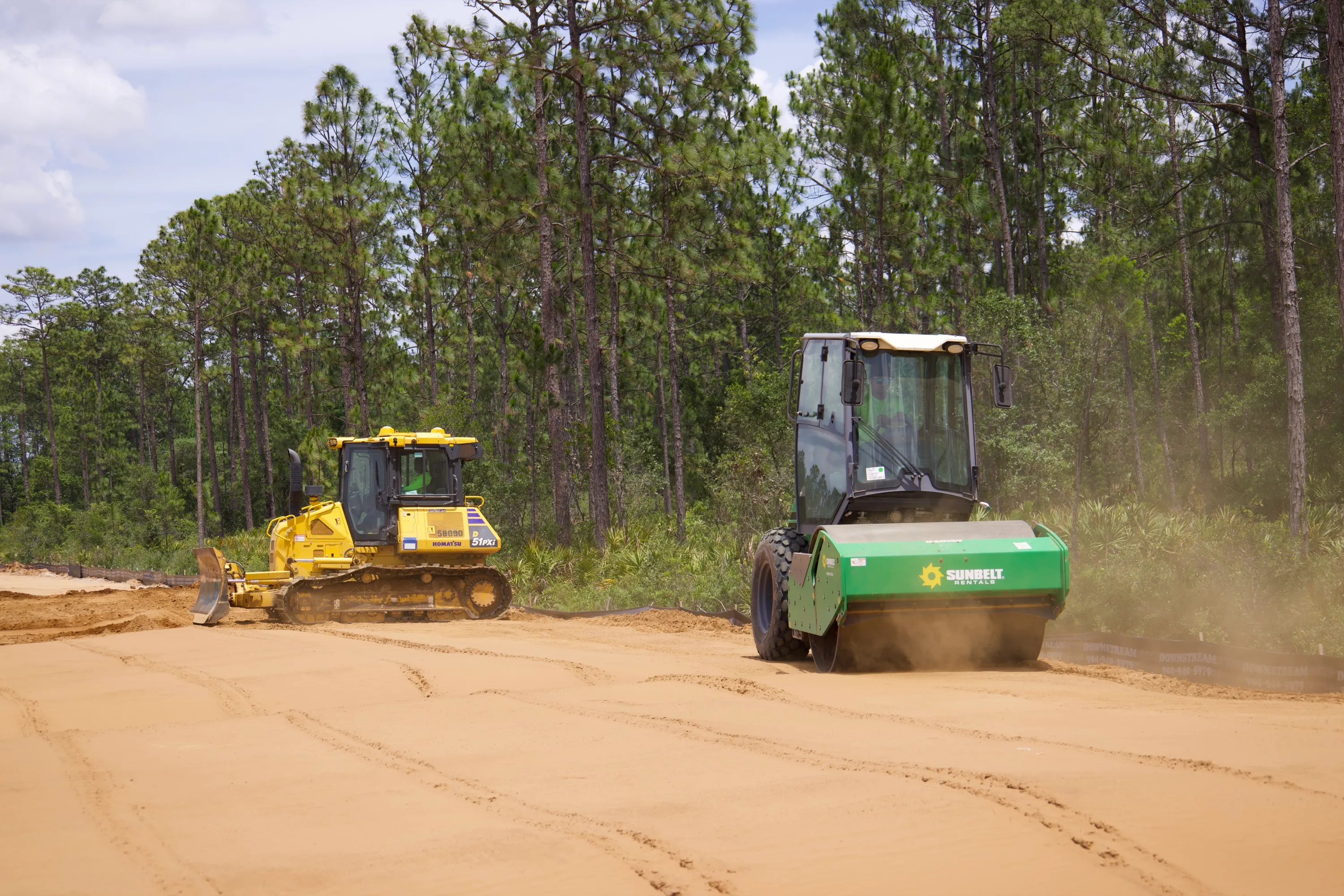 Dozer and roller setting final grade on a cleared site